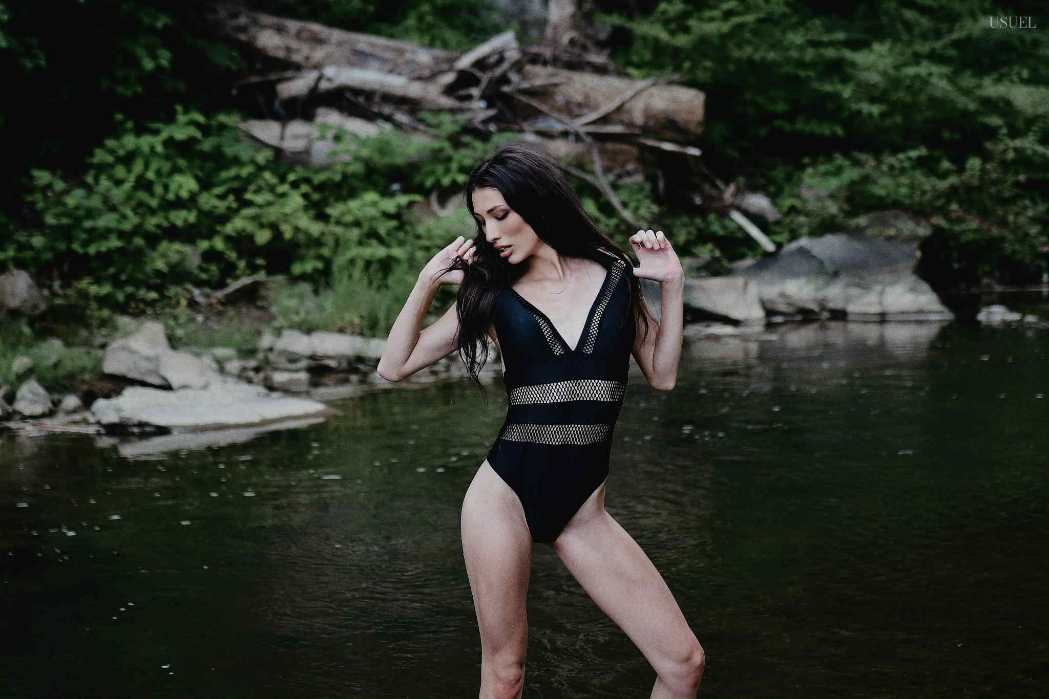 Brunette woman in a black swimsuit standing and moving gracefully in the North Fork Kentucky River