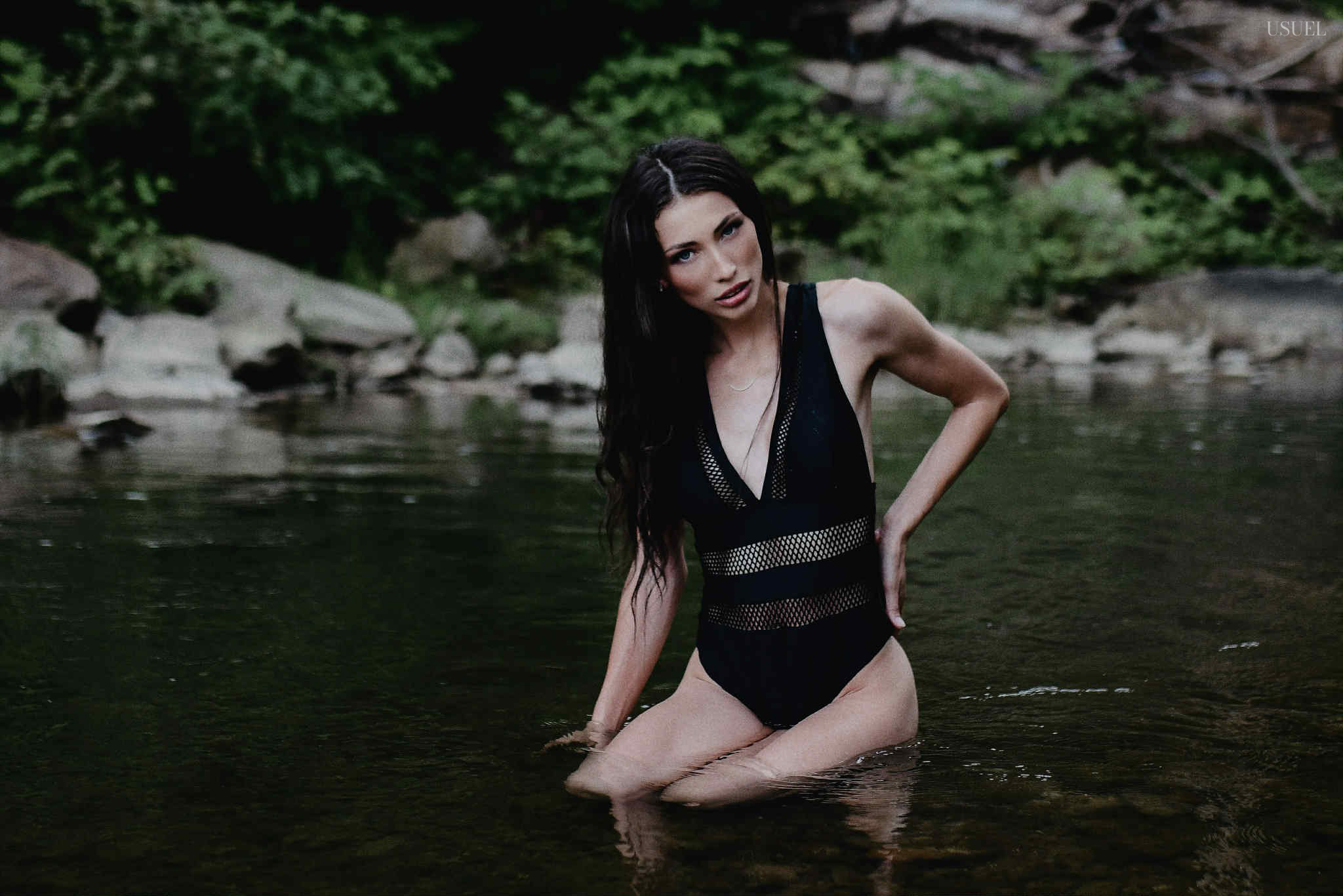 Brunette woman in a black swimsuit standing and moving gracefully in the North Fork Kentucky River