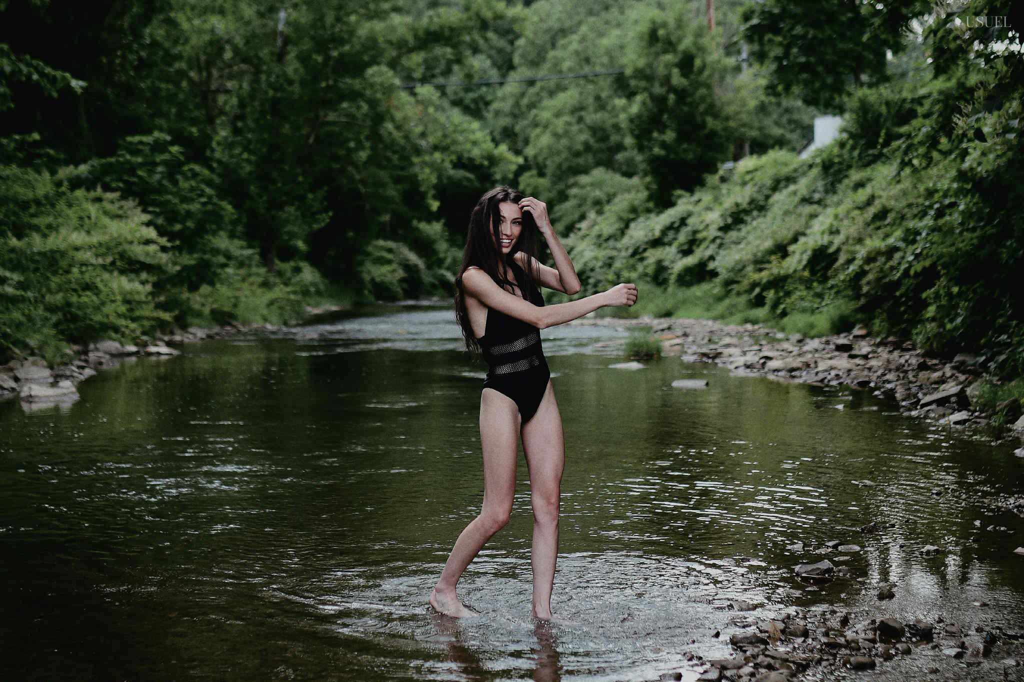 Brunette woman in a black swimsuit standing and moving gracefully in the North Fork Kentucky River