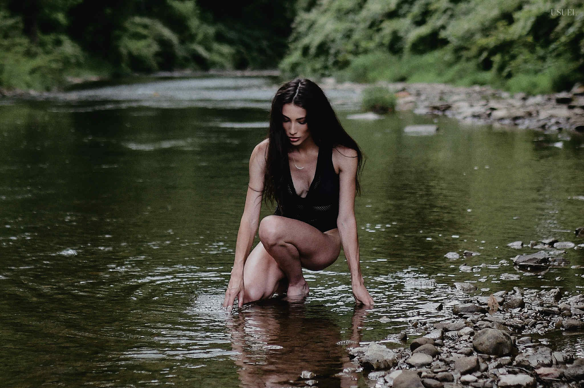 Brunette woman in a black swimsuit standing and moving gracefully in the North Fork Kentucky River