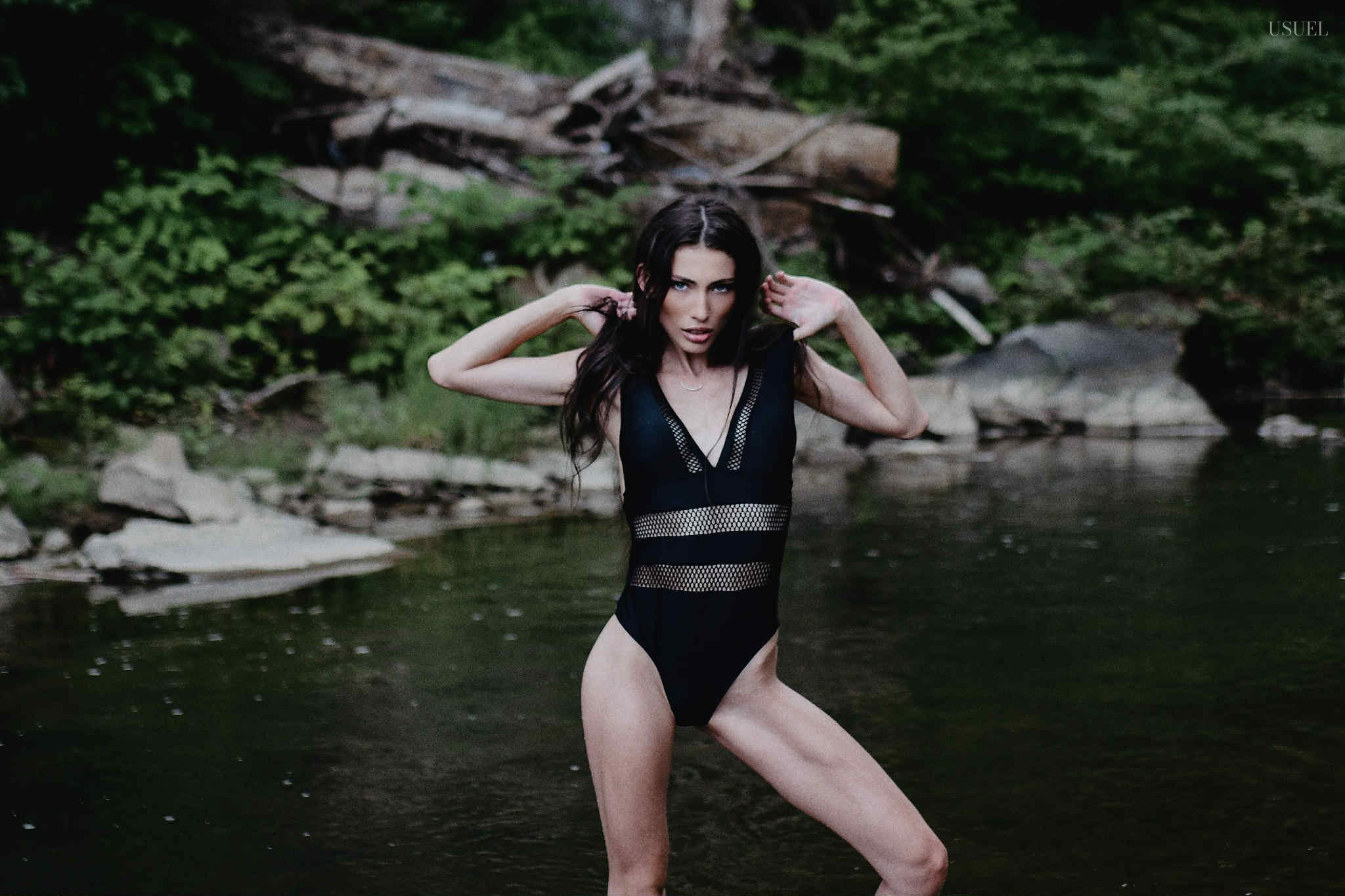 Brunette woman in a black swimsuit standing and moving gracefully in the North Fork Kentucky River