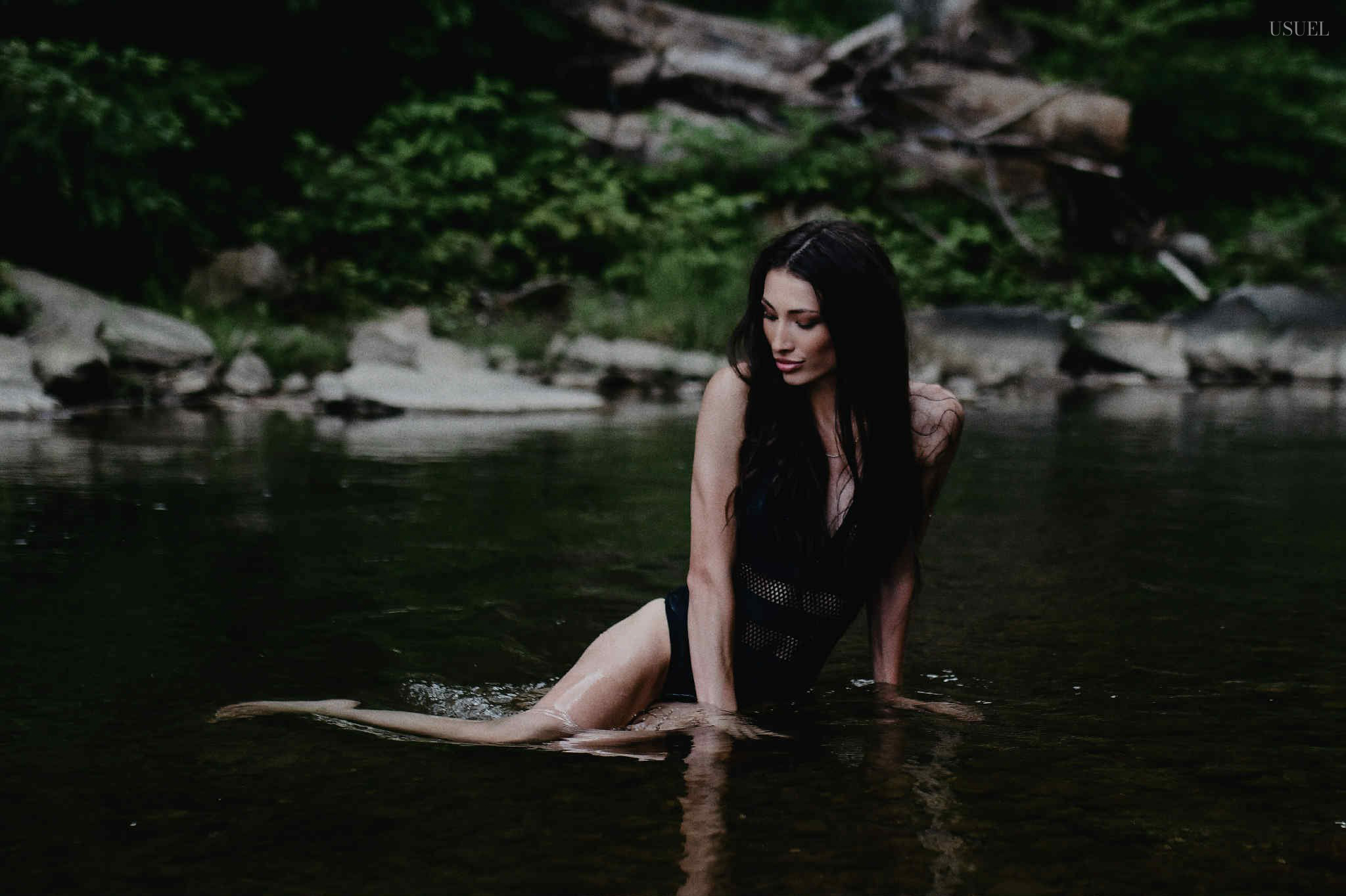 Brunette woman in a black swimsuit standing and moving gracefully in the North Fork Kentucky River