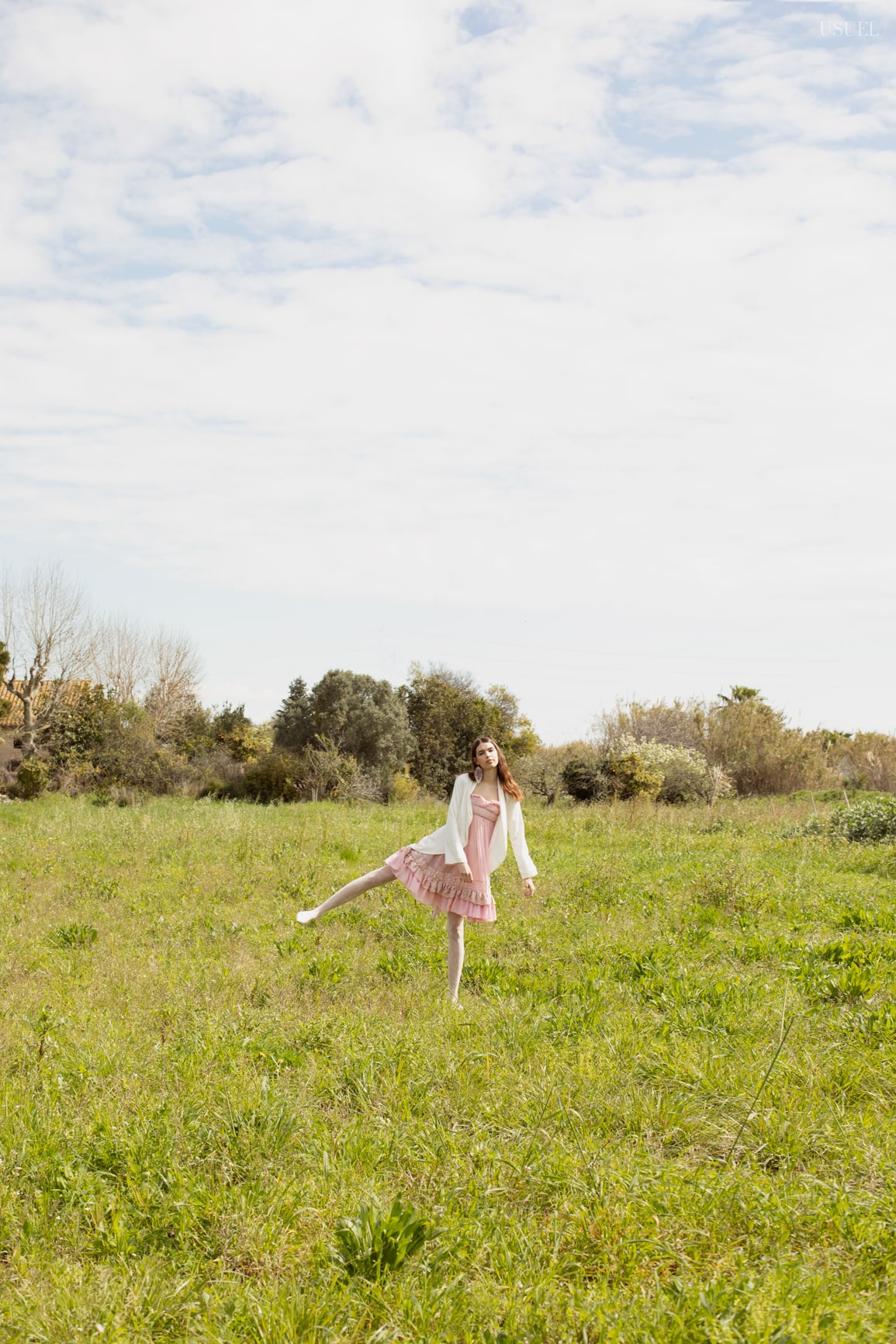 Model Lina wearing light, flowing garments made of tulle and lace, standing in the grass.