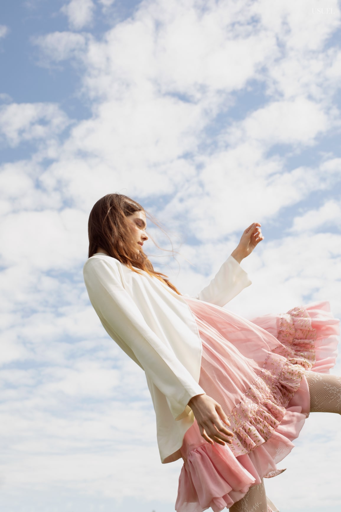 Model Lina wearing light, flowing garments made of tulle and lace, standing in the grass.