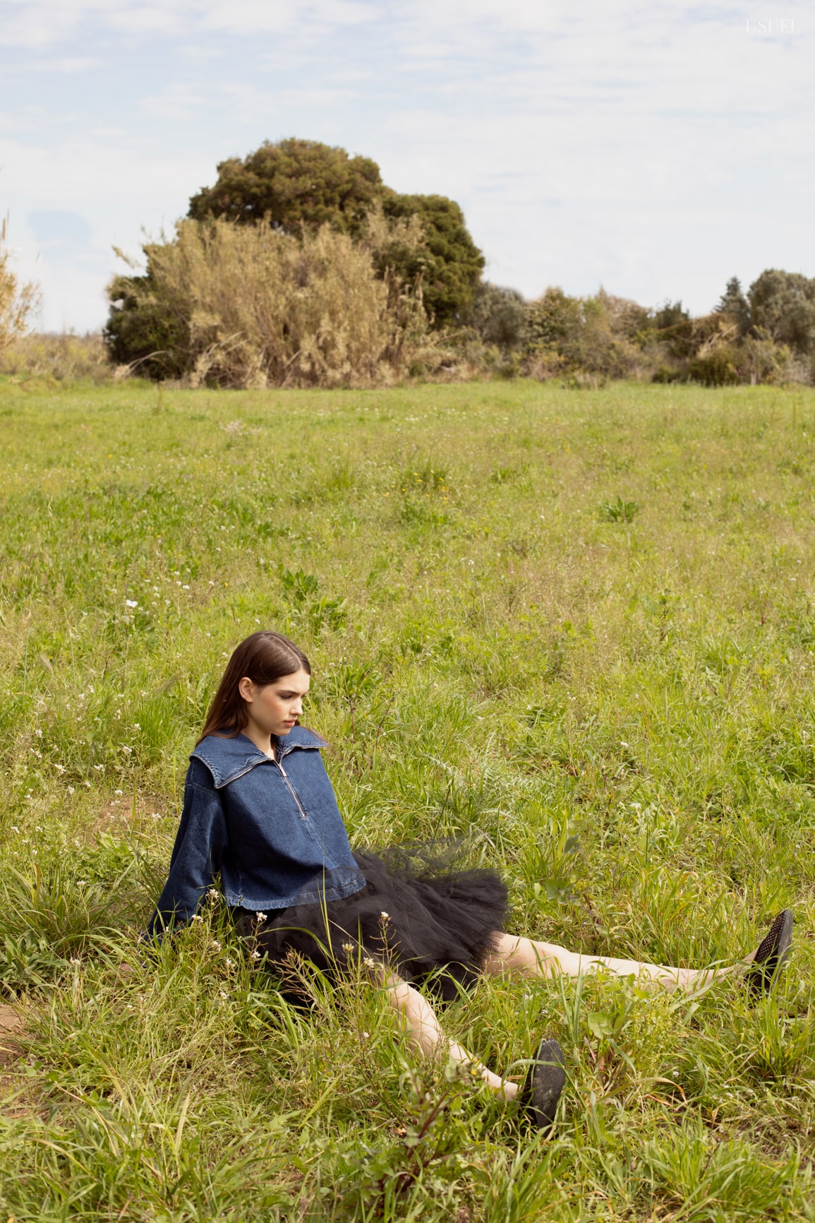Model Lina wearing light, flowing garments made of tulle and lace, standing in the grass.