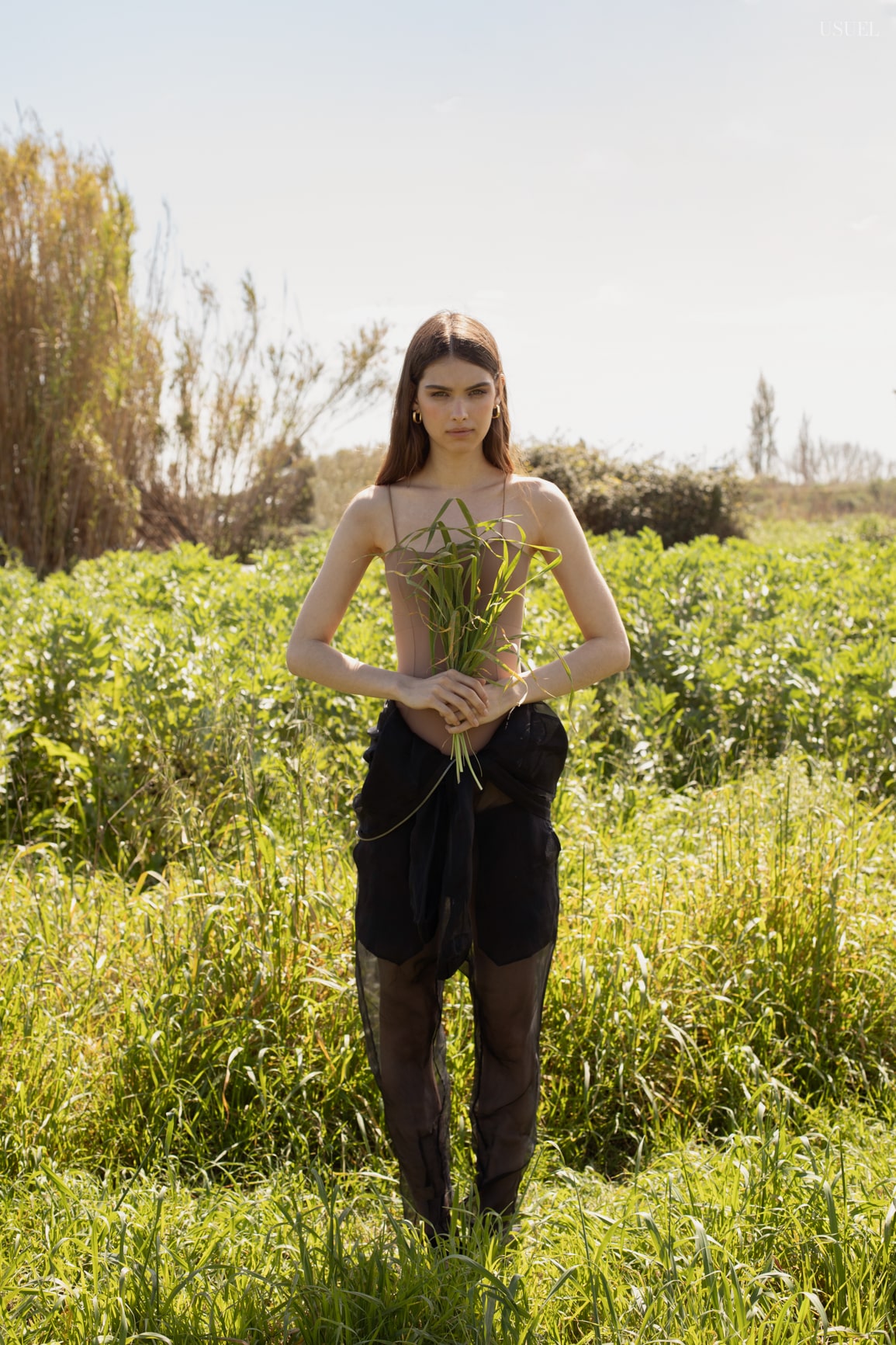 Model Lina wearing light, flowing garments made of tulle and lace, standing in the grass.