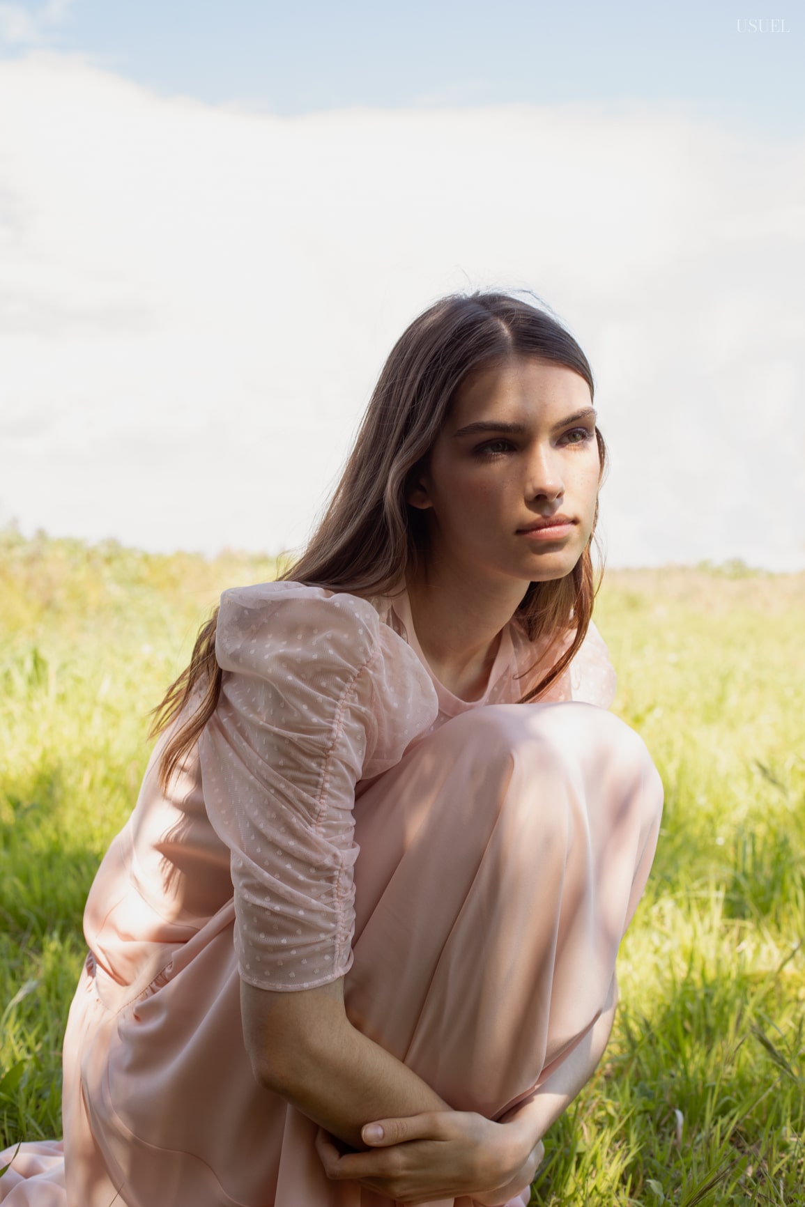 Model Lina wearing light, flowing garments made of tulle and lace, standing in the grass.