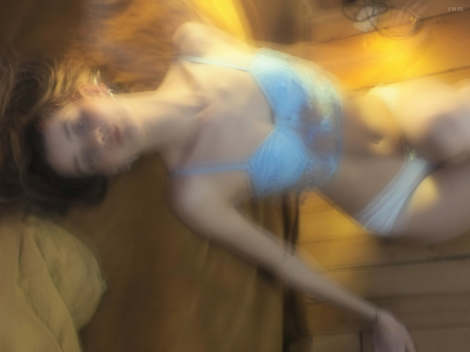 Woman in light blue lingerie lying on a wooden floor