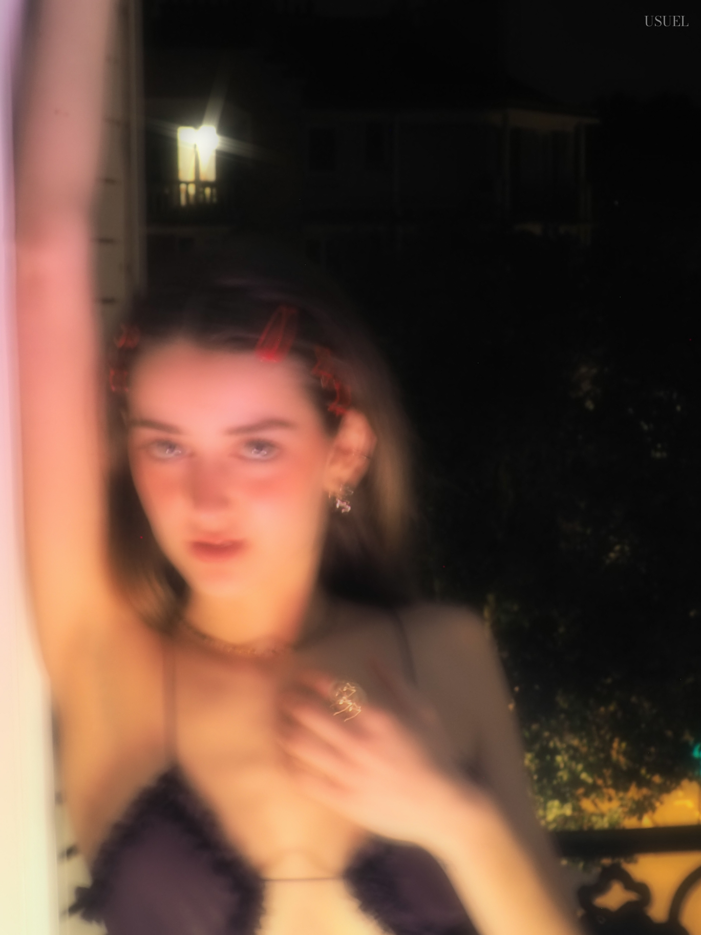 Woman in a purple dress posing near a window at night