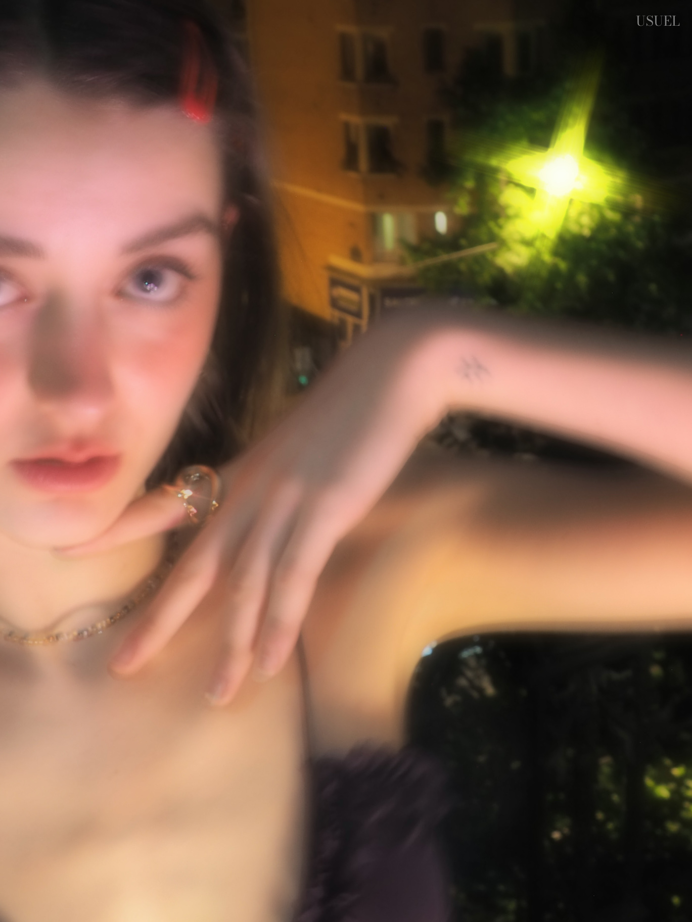 Woman in a purple dress posing near a window at night