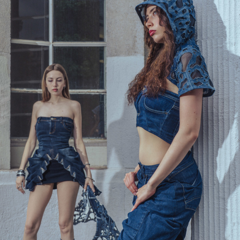 Two women wearing denim outfits, standing close to each other in an expressive pose