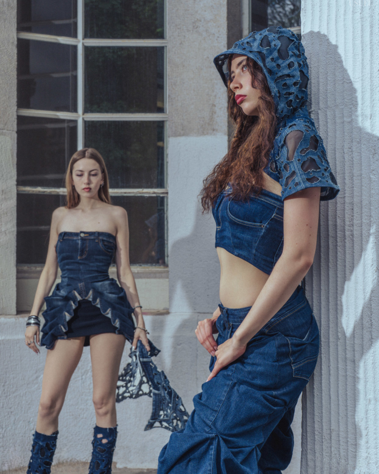Two women wearing denim outfits, standing close to each other in an expressive pose