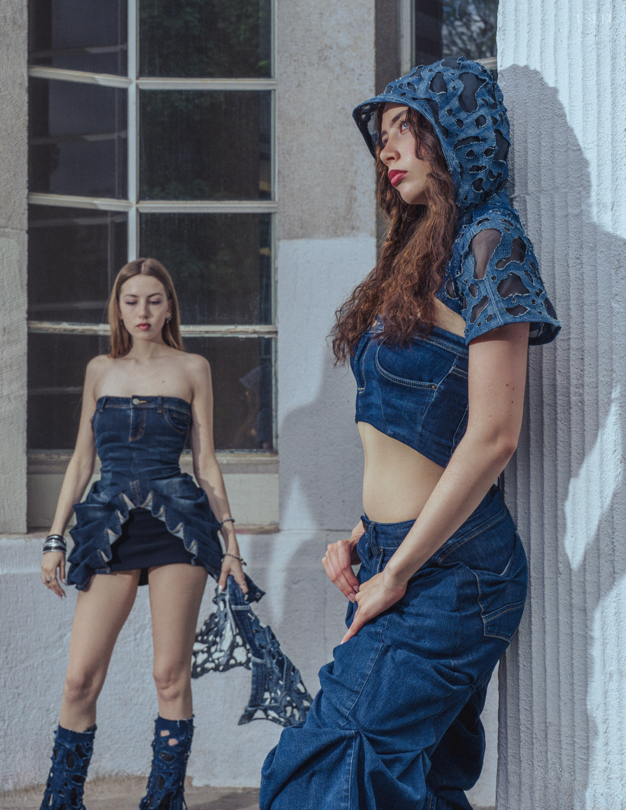 Two women wearing denim outfits, standing close to each other in an expressive pose