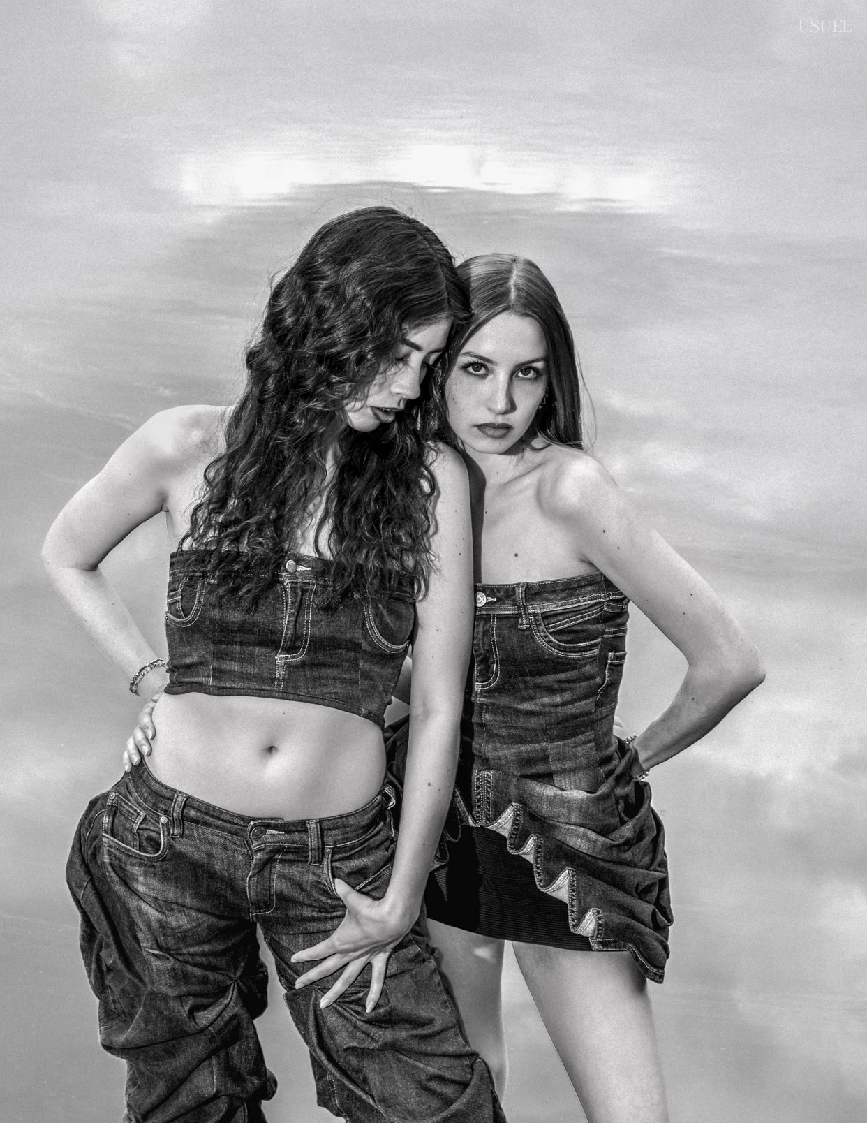Two women wearing denim outfits, standing close to each other in an expressive pose